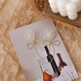 Elegant white flower and gold-plated bow drop earrings highlights their delicate craftsmanship.